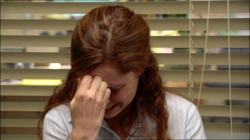 Pam from the office, looking down with her hand on her forehead