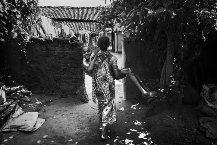 Rakesh being carried by his mother for a bath in Bango village