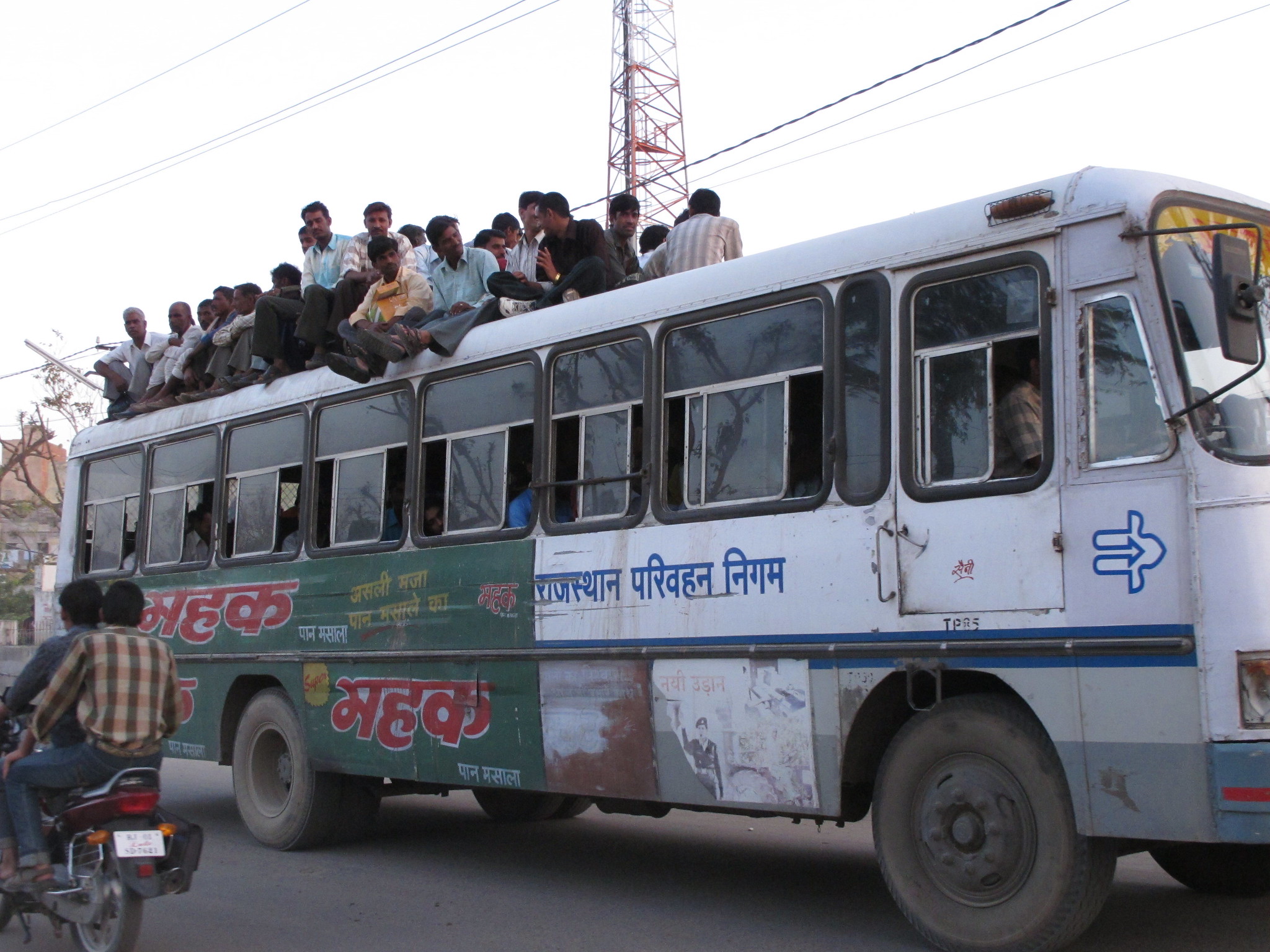 A crowded bus in India with people sitting on the roof