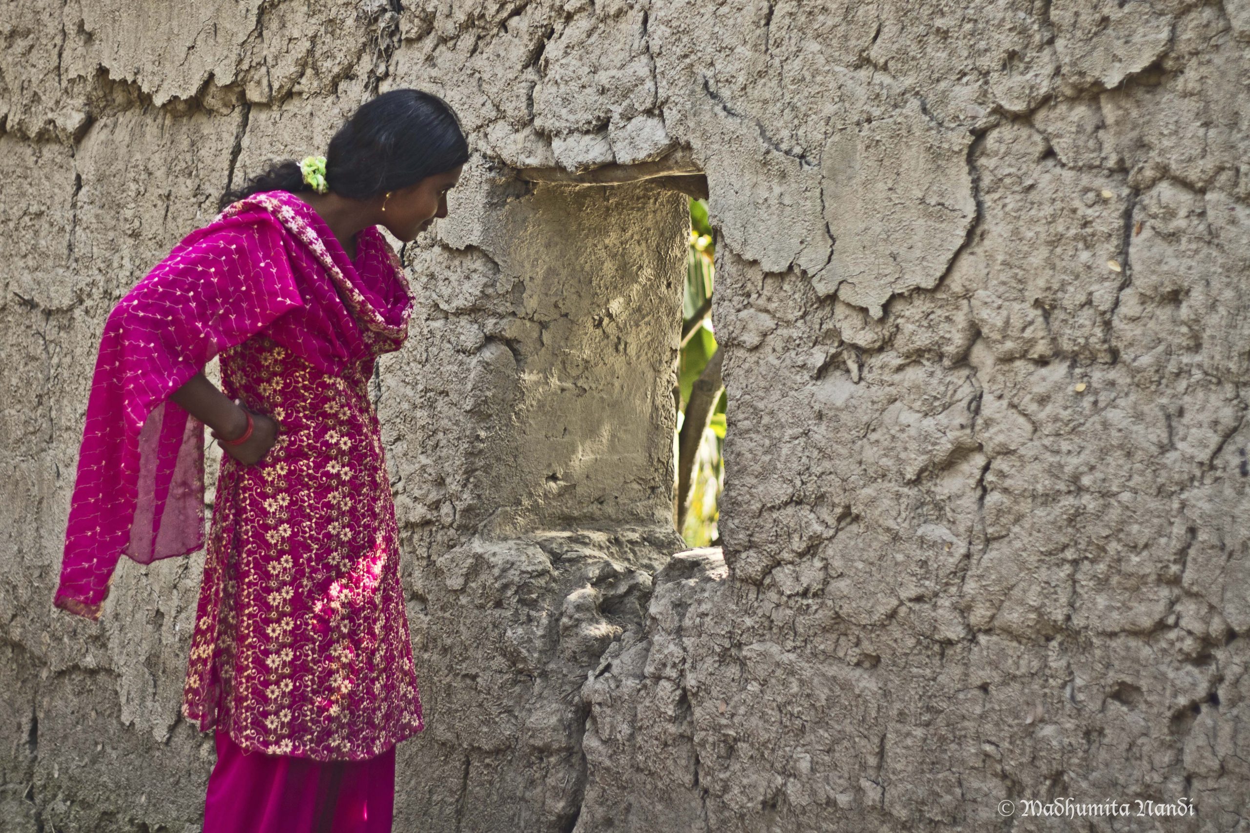 An Indian woman looking outside a window in a wall