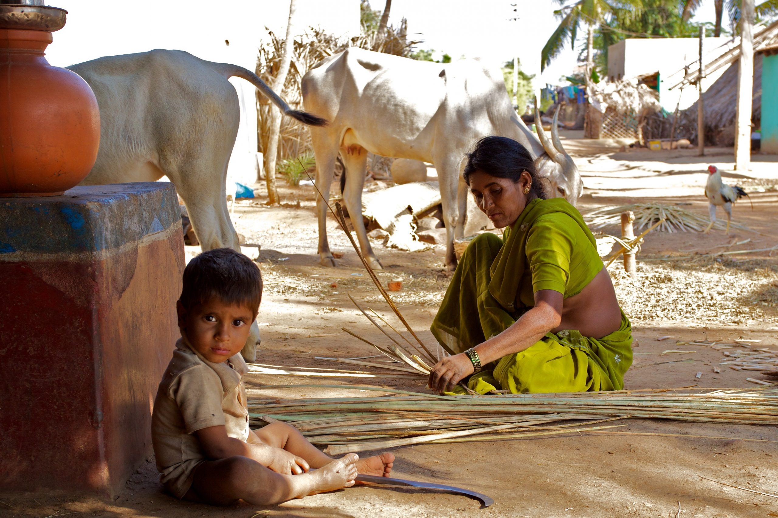 gender inequality_an Indian woman weaving a basket next to her baby