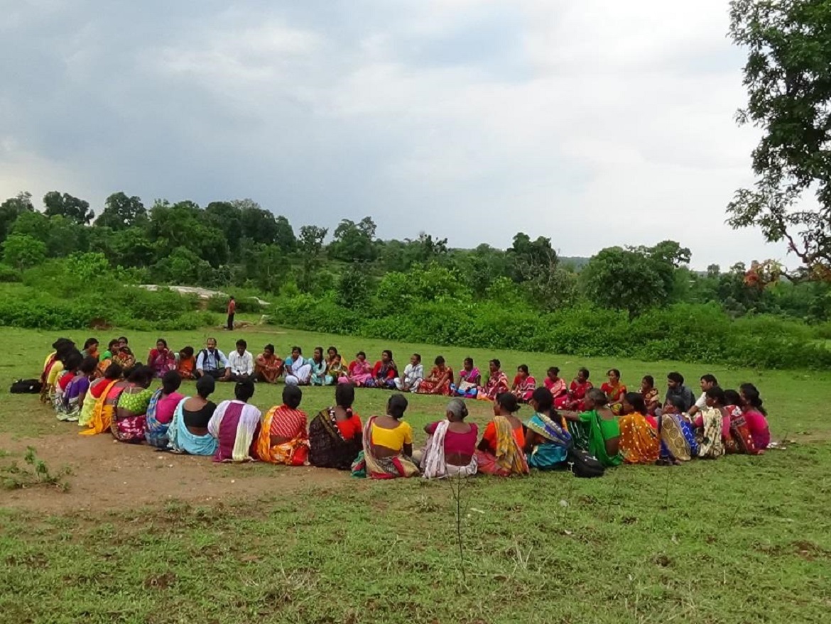 Several villagers sitting in a circle