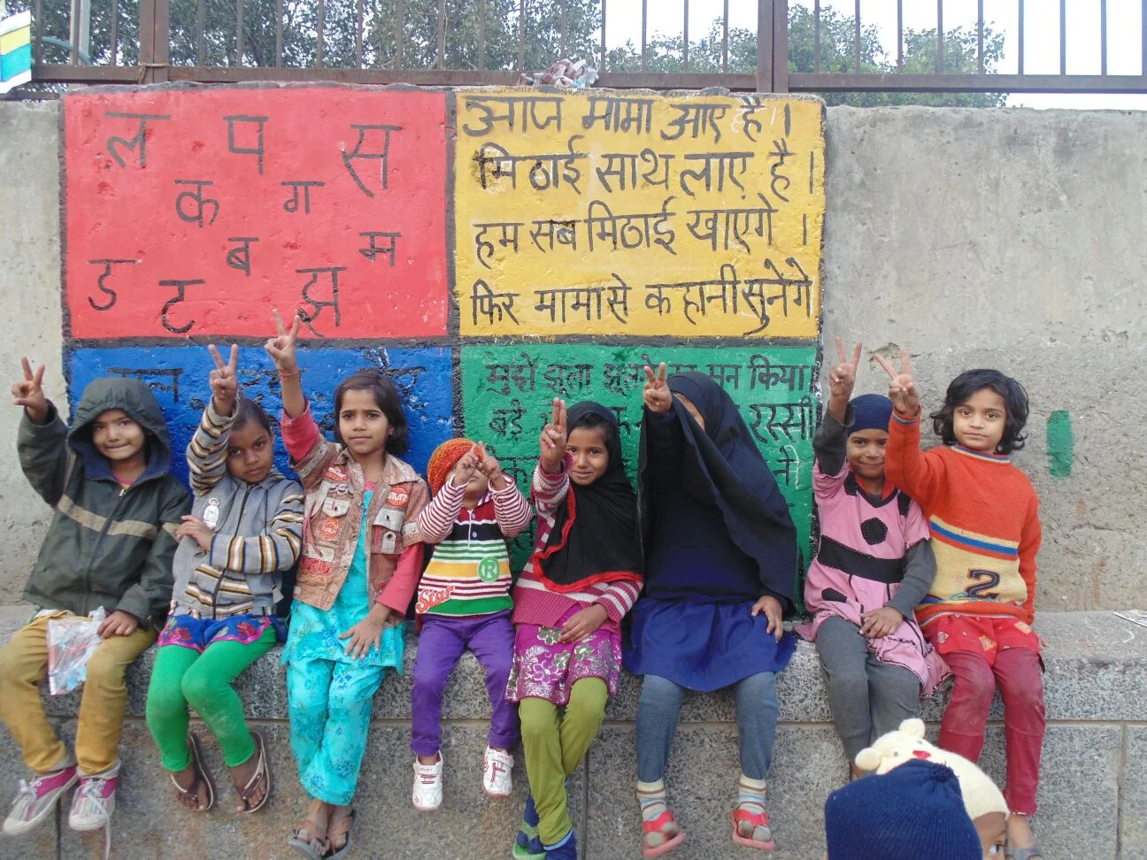School-going kids in front of brightly painted wall