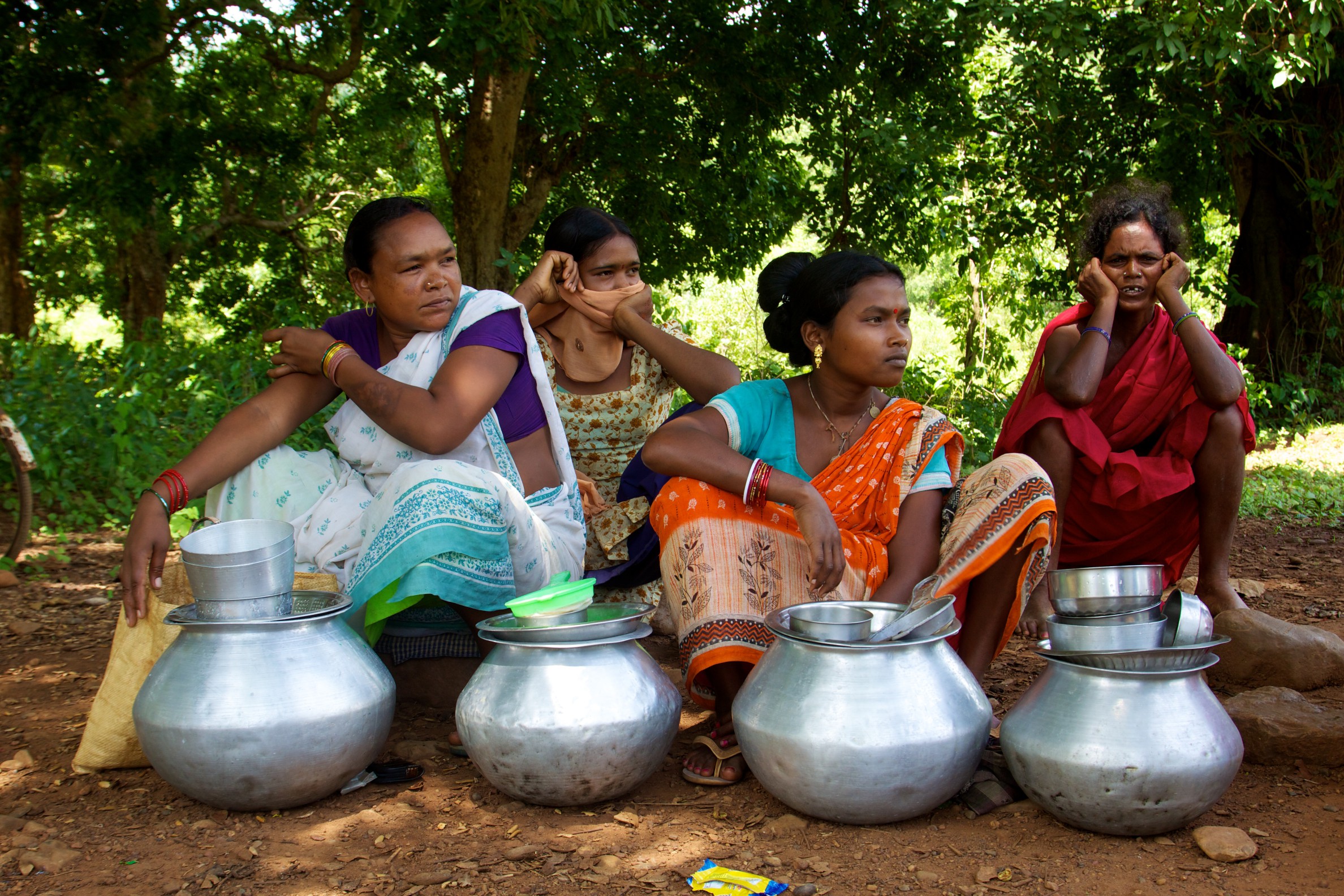 4 women sitting with metal pots