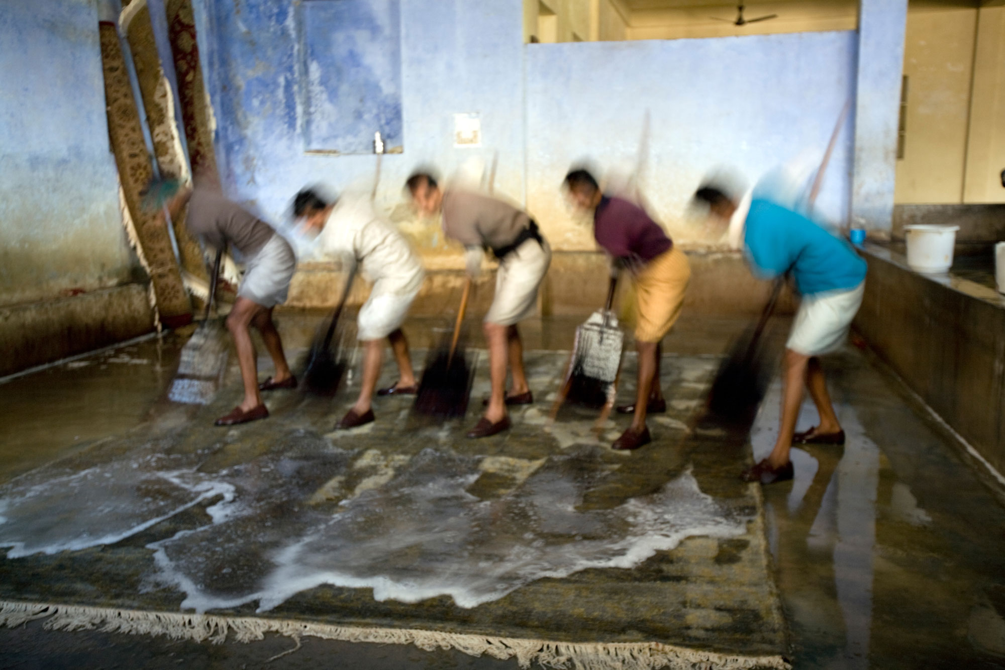 Indian men sweeping rugs