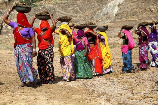 Village women working under NREGA carrying load and walking in a line with their sarees covering their faces-photo credit PTI