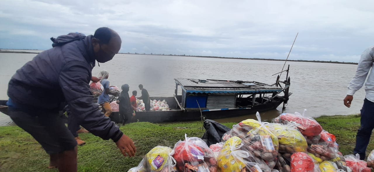 picture of a relief worker standing next to a boat and loading relief material-floods in assam-COVID-19