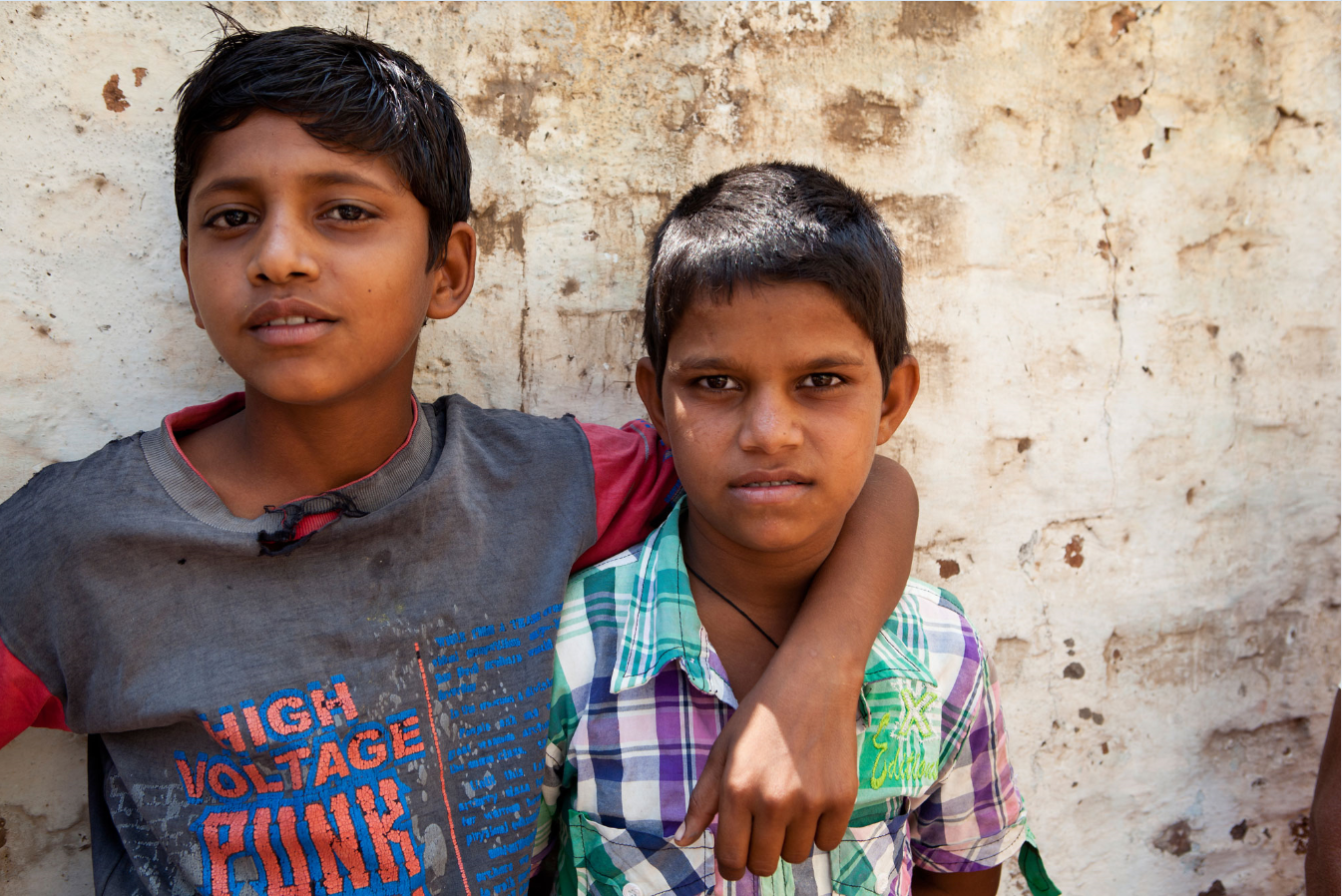 Two young men standing against a wall in India