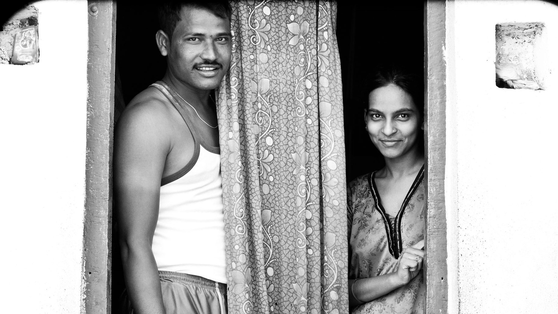 A man and woman standing at the entrance of a house