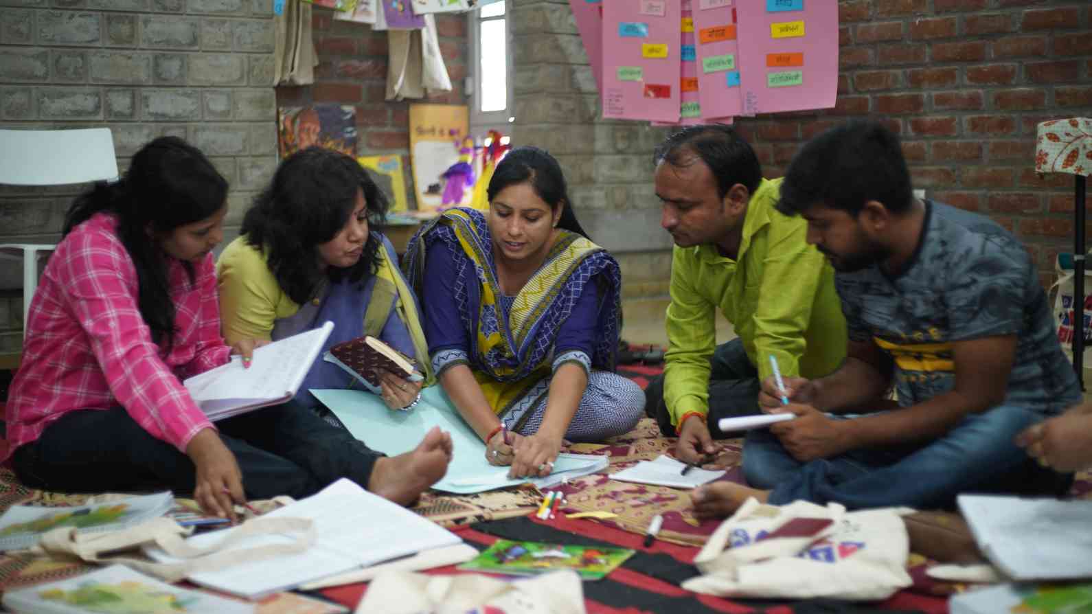 group of five people sitting together at a teacher training session, surrounded by books-teacher training