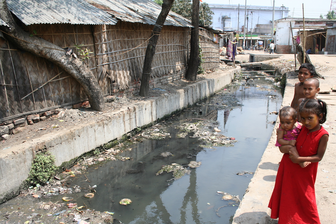 4 children standing near a polluted water body