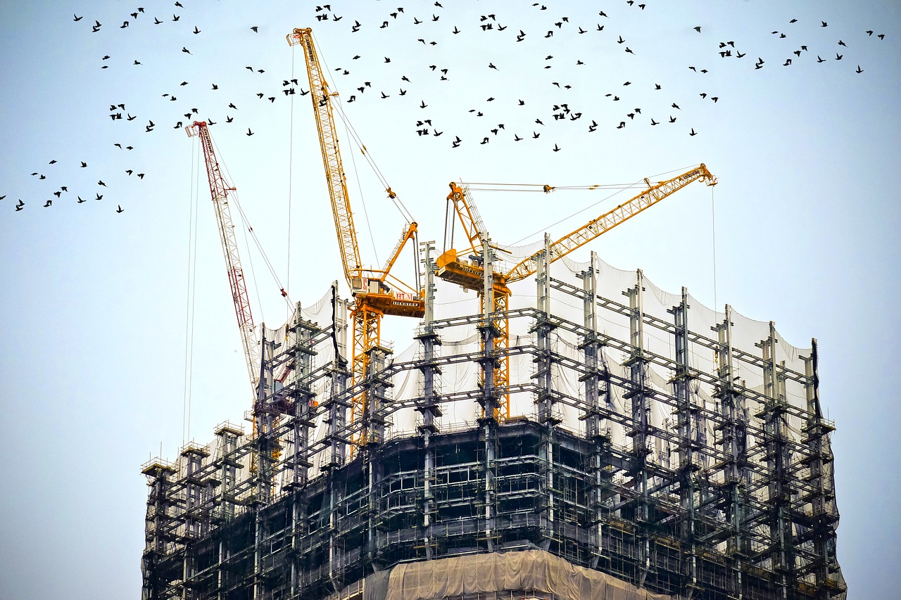 A building under construction in a city with many cranes