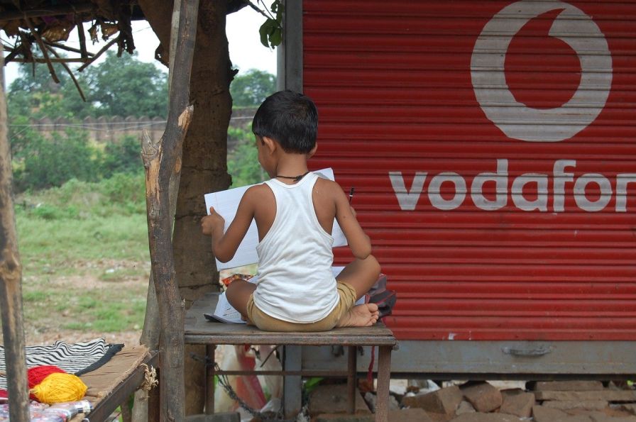 child sitting on a table and doing homework-education