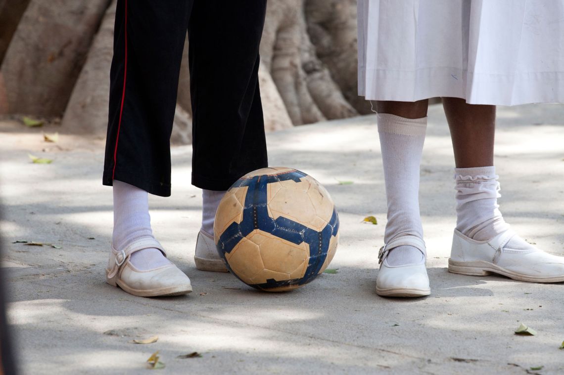 close up of football with the feet of school children. Play is an important aspect of a child's learning