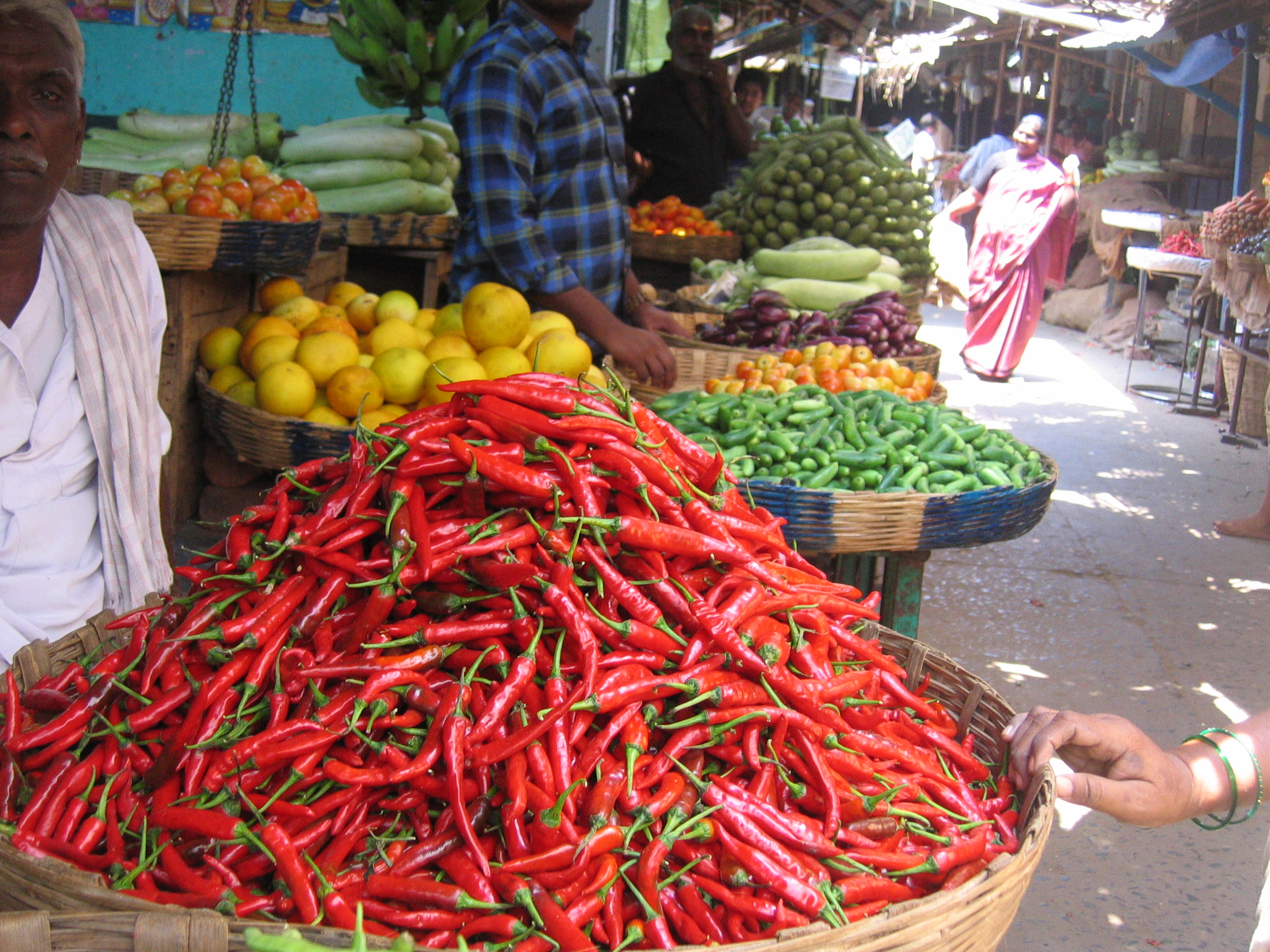 Vegetable market with baskets full of chillies and other vegetables