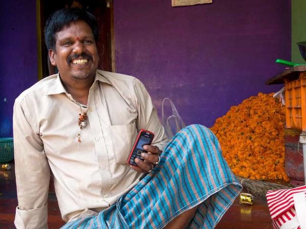 man happily holding a mobile phone in his hand Omidyar