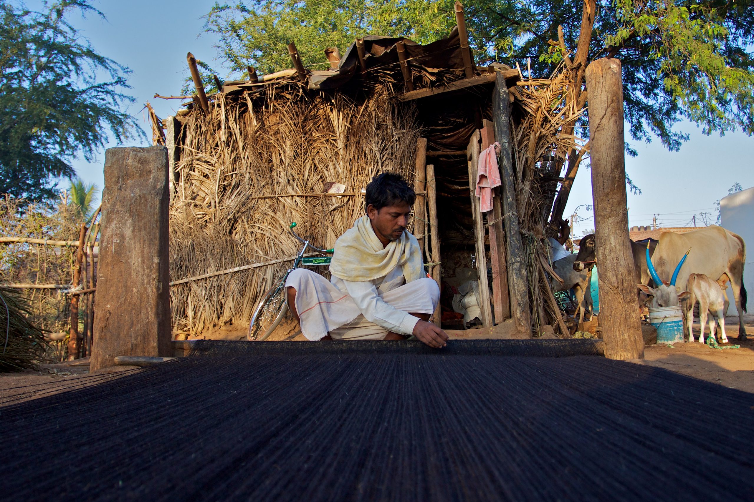 A man in rural India weaving a rug 