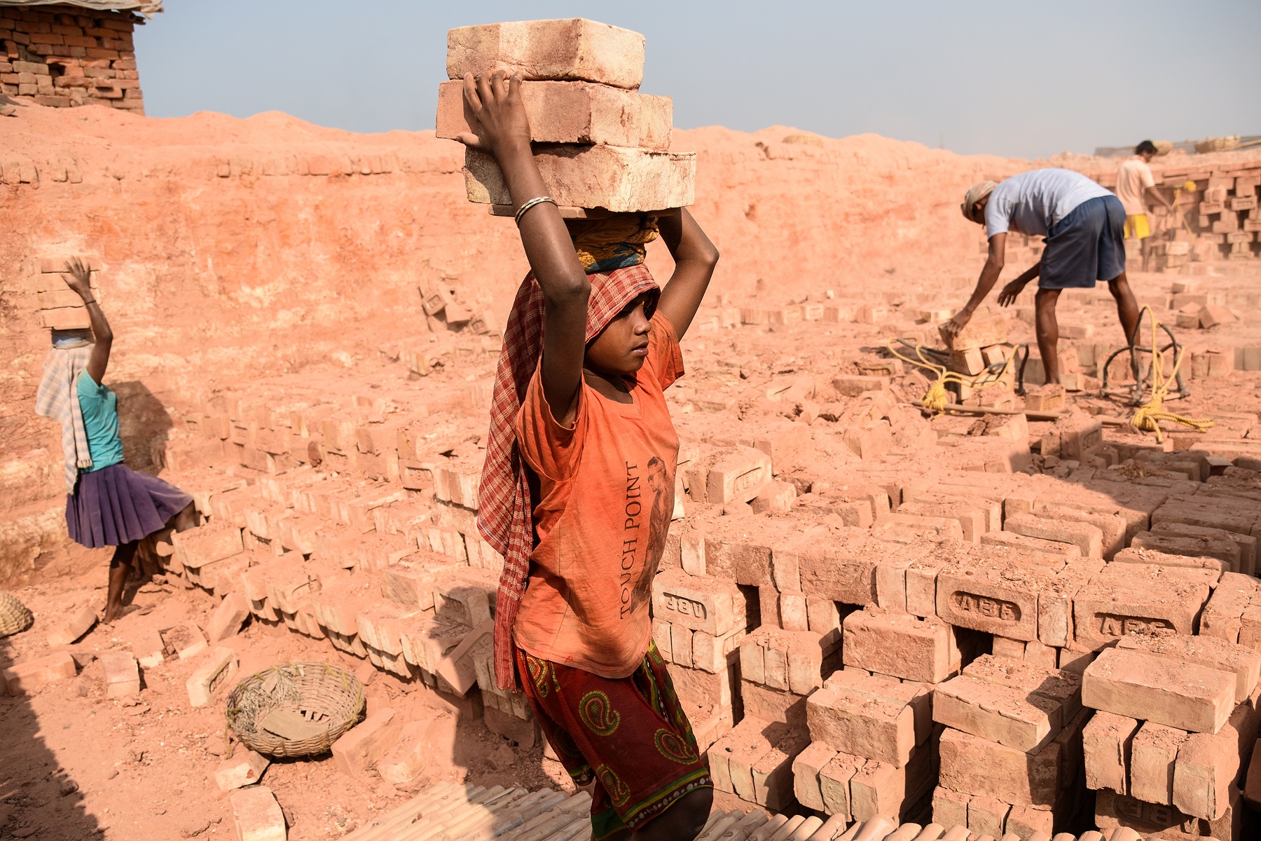 A female child labourer with bricks on her head