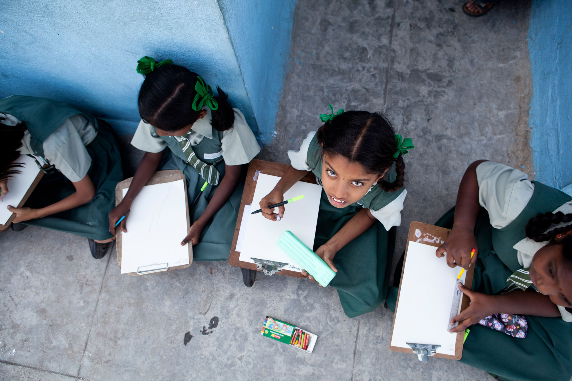 Arial shot of Indian school girls sitting on the floor doing homework_private schools