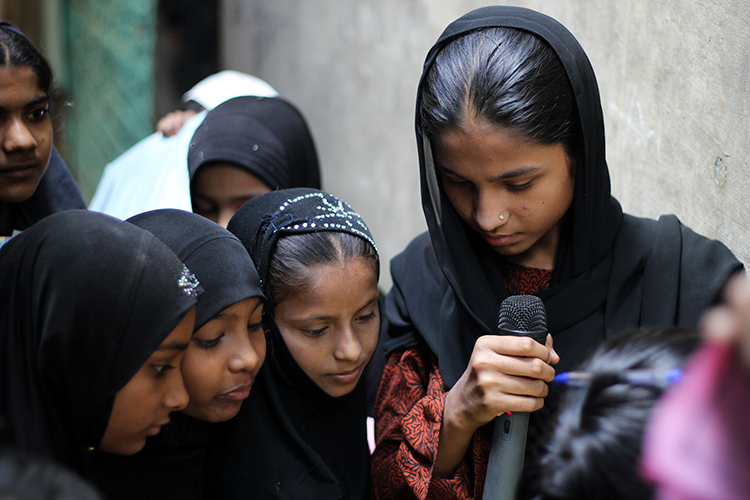 A group of young girls clustered around a mic