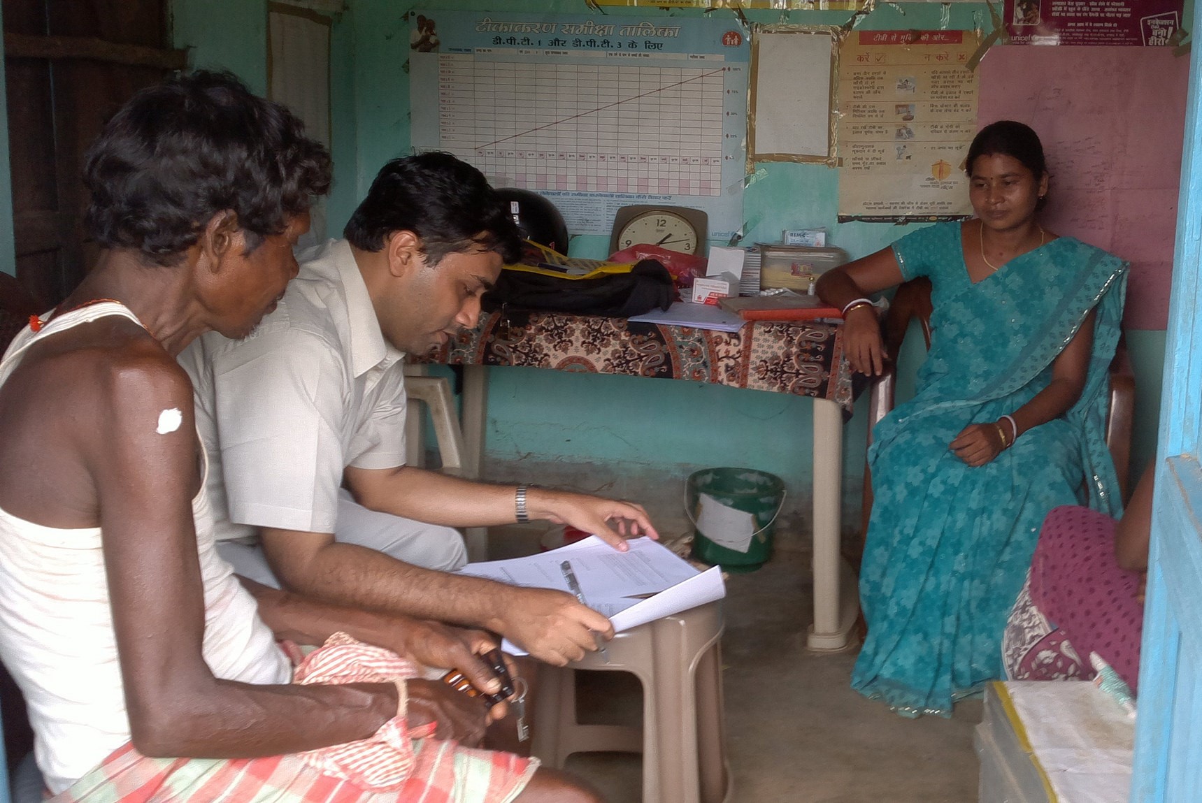 An official taking some details from 2 villagers