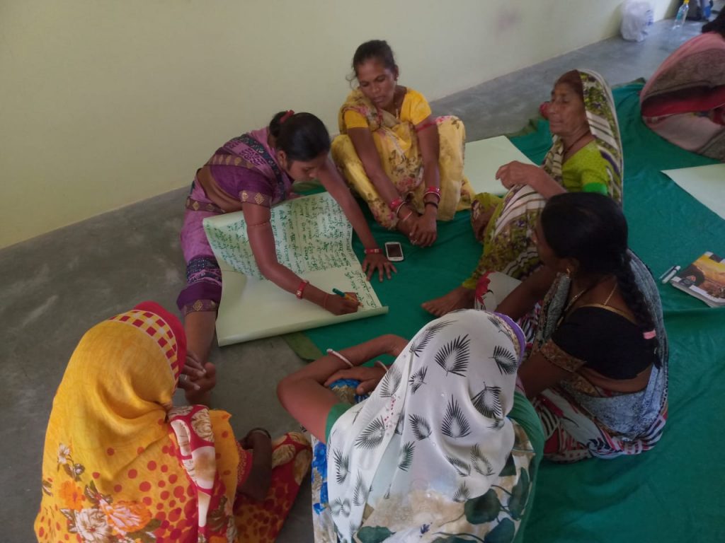 Kokila sitting and filling out a register among a group of women-domestic violence