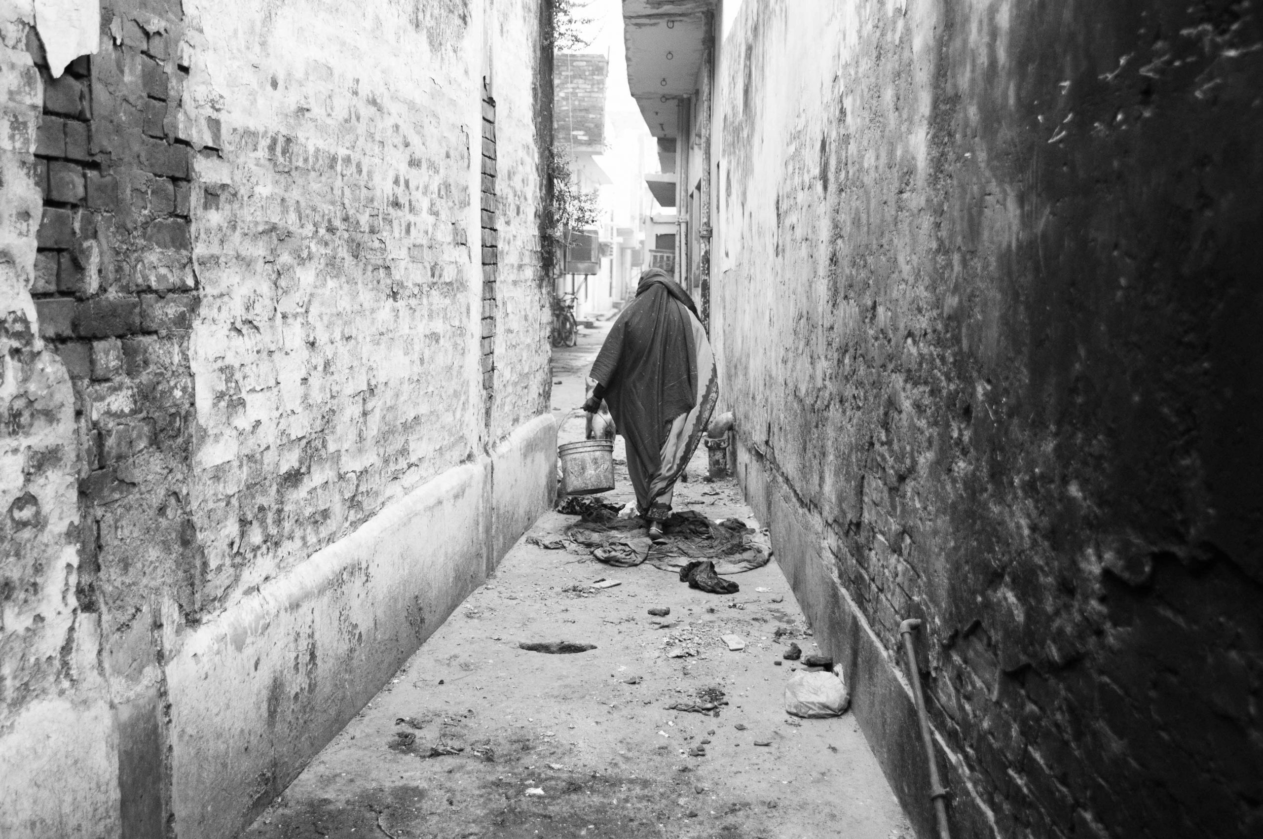 woman carrying buckets in alley