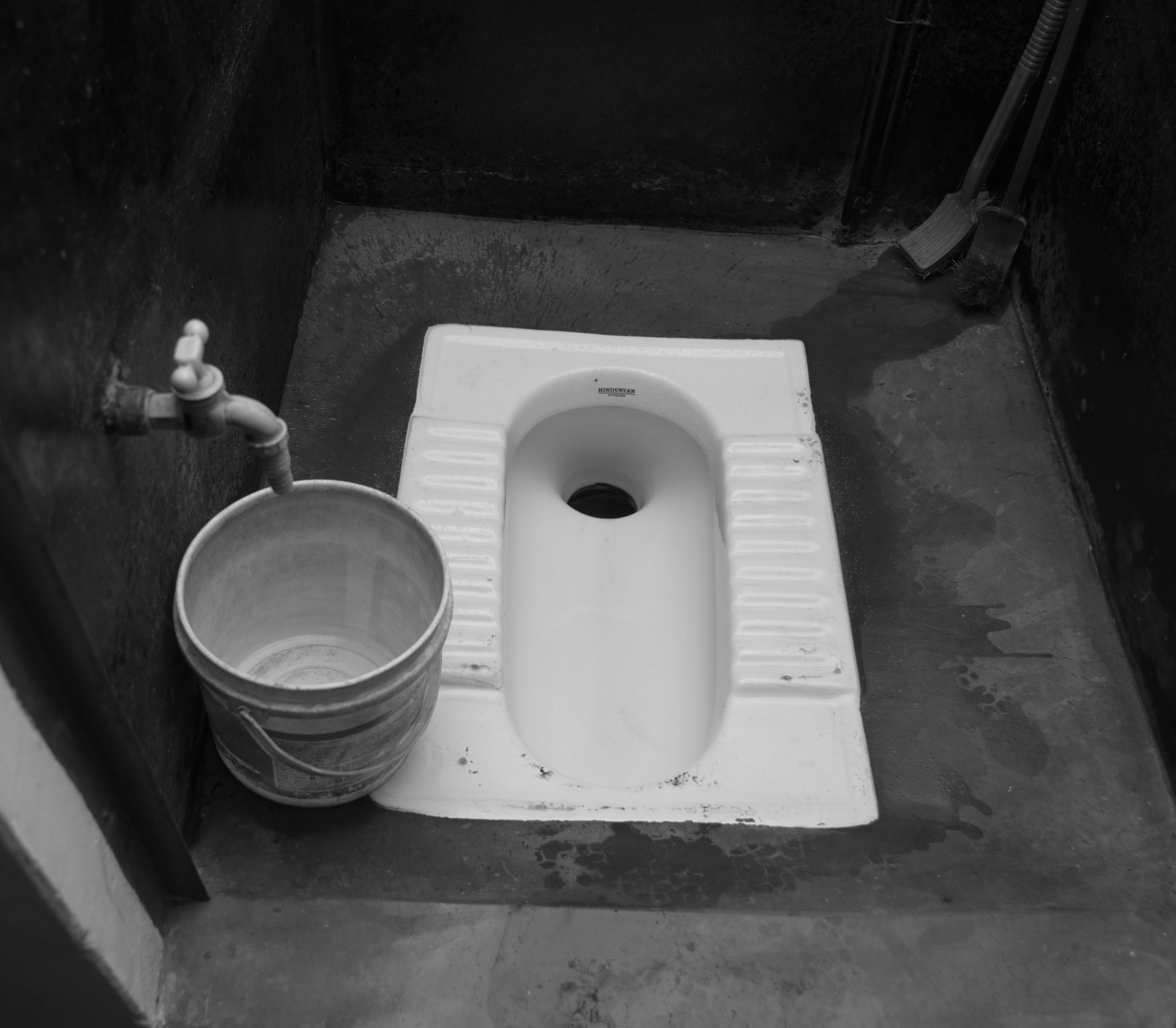 indian toilet in ground with bucket