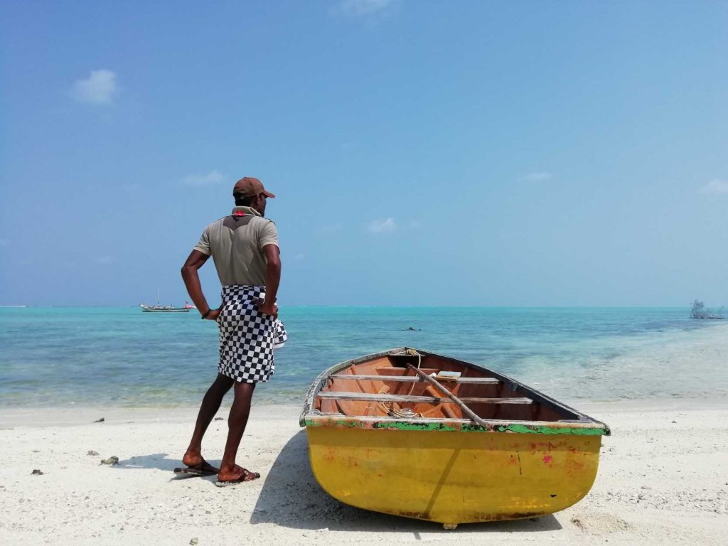 man standing by a small boat in the Lakshwadeep islands-fisheries