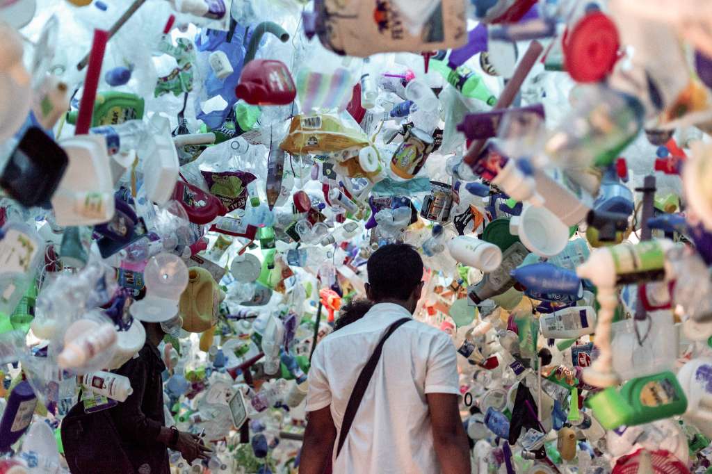 man walking through an exhibition surrounded by plastic-waste management