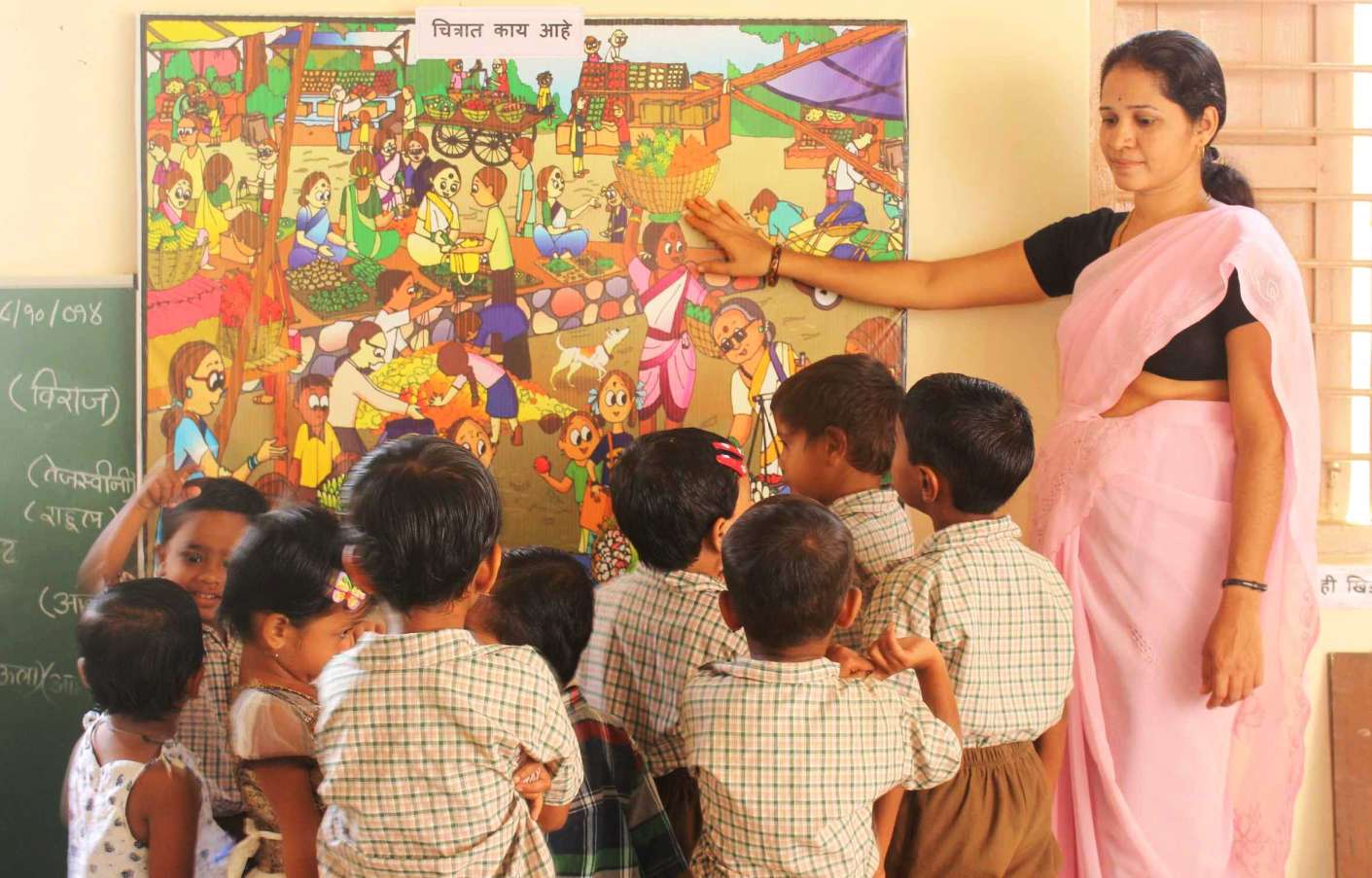 teacher pointing at a chart surrounded by a group of students_QUEST