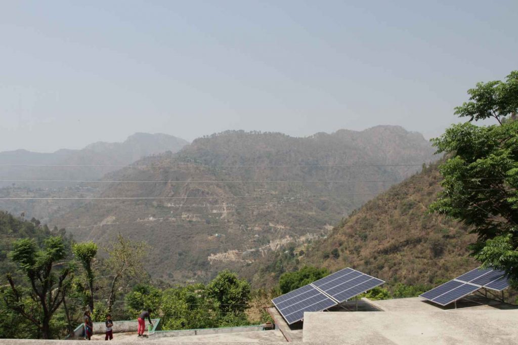 Power Farmers solar panels near Khadi overlooking hills with people standing near by- self-employment