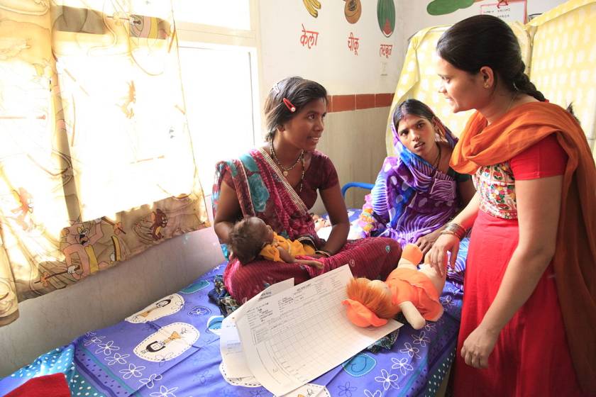 Woman holding a baby in the hospital with two women around-maternity benefits