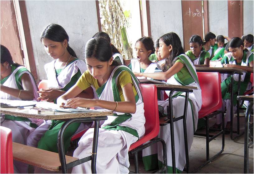 Students wearing uniforms sitting on benches next to each other writing-board exams