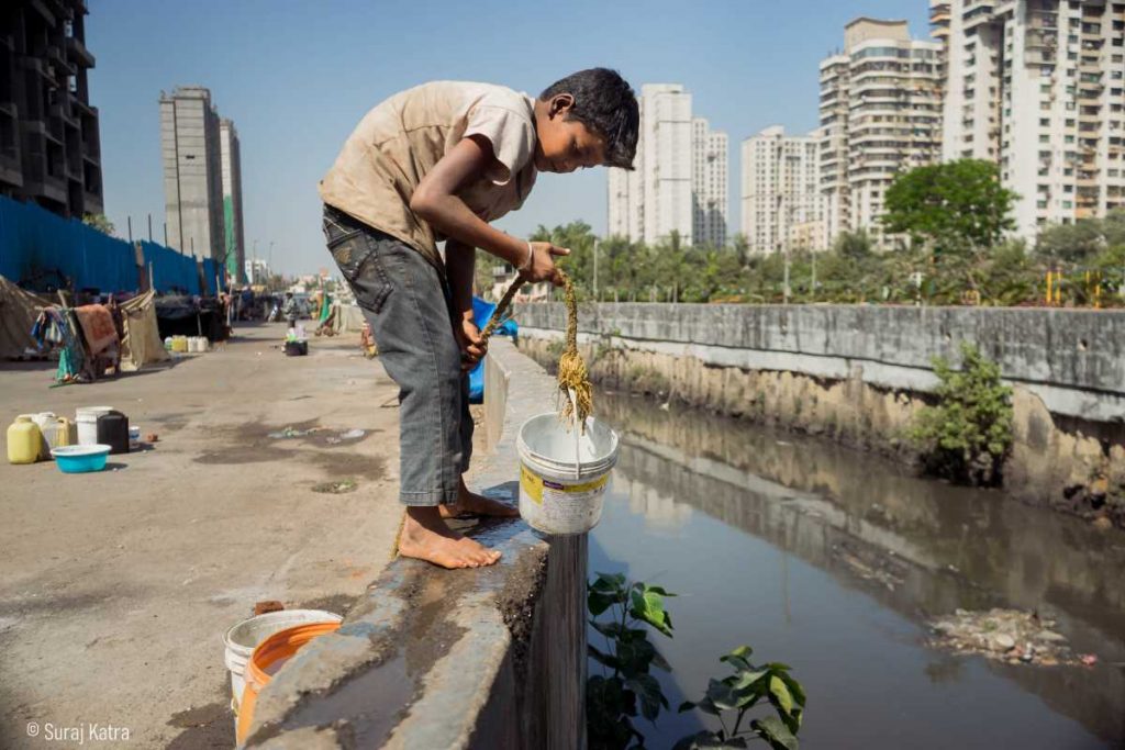 Image 14_a boy holding a bucket next to a sewer_water for all_picture courtesy Suraj Katra