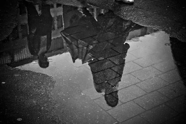 black and white image of a person reflected in a puddle-social change fellowship
