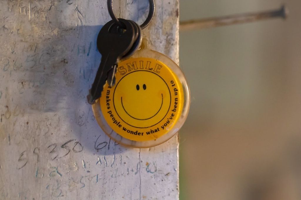 a round yellow keychain with a smiley drawn on it