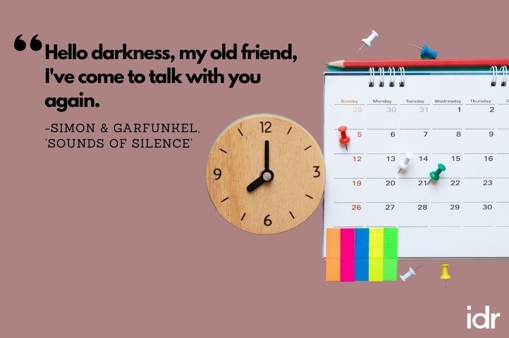 There is a calendar, with a pencil on top, push pins on it, and some post it notes stuck on the bottom. On its left, there is a clock. The quote on the image reads, "Hello darkness, my old friend, I've come to talk with you again. By Simon and Garfunkel, "Sounds of silence"-workweek playlist