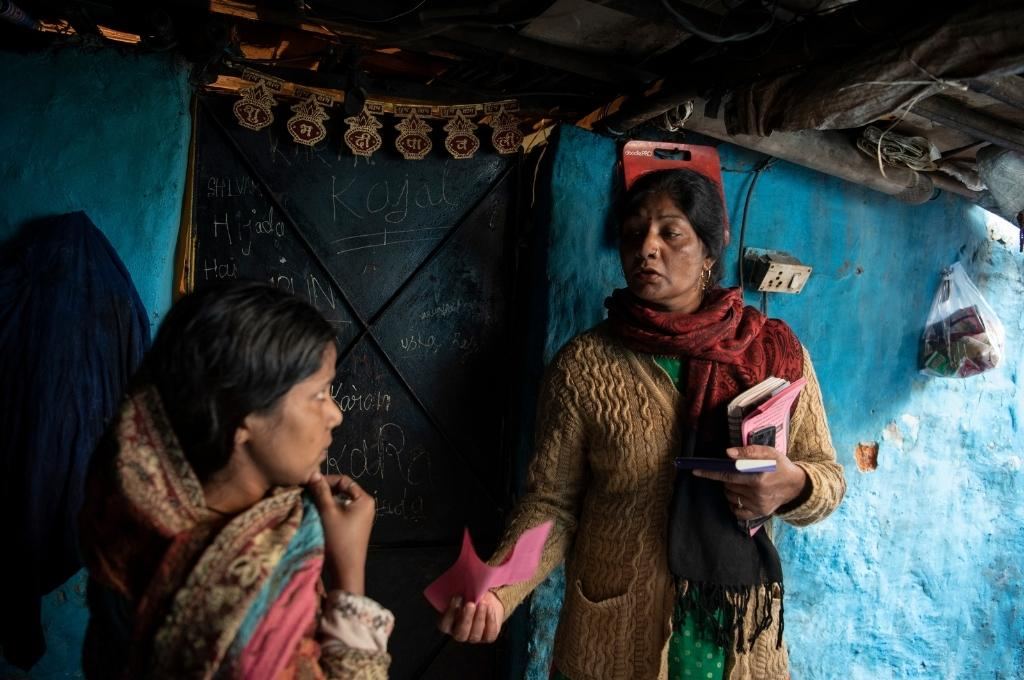 Field worker from Haqdarshak (an organisation) showing pink slip to woman-upskilling field workers