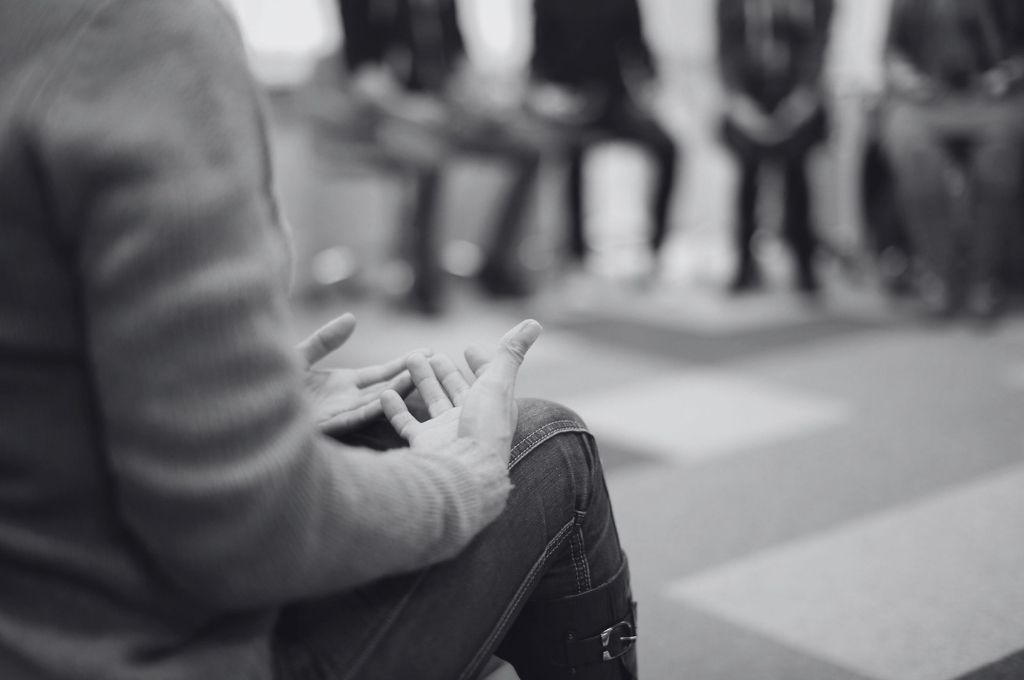 Image of the hands of a person at a group therapy session. Suicide prevention requires community effort and policy changes