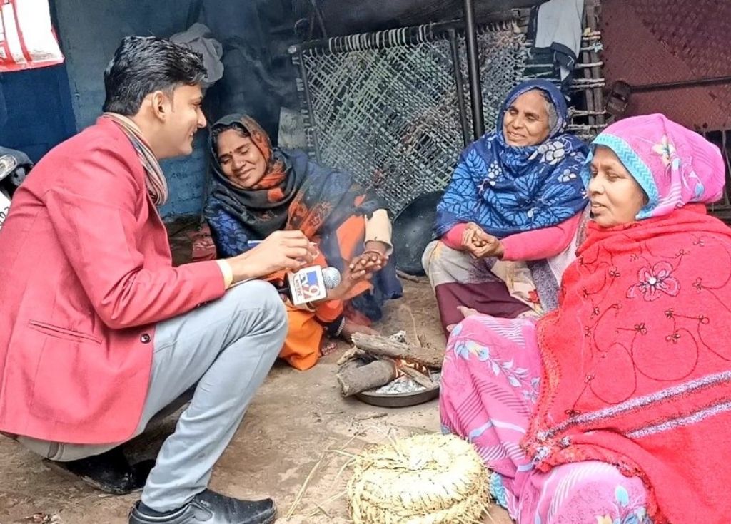 A male journalist with a mic speaking with three women