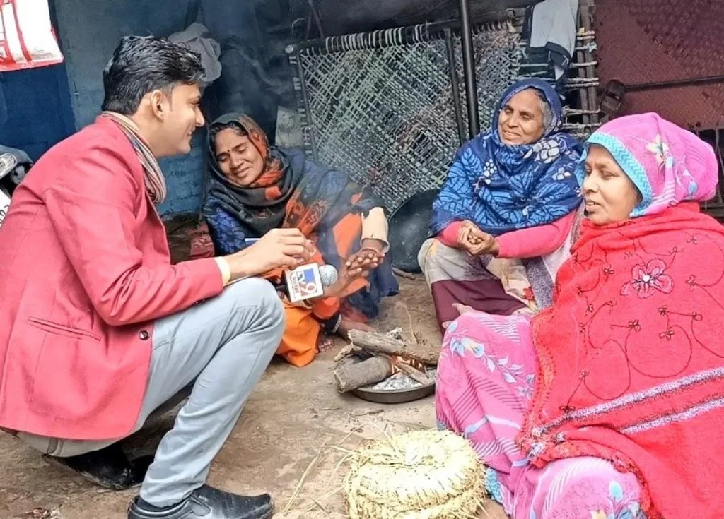 A male journalist with a mic speaking with three women