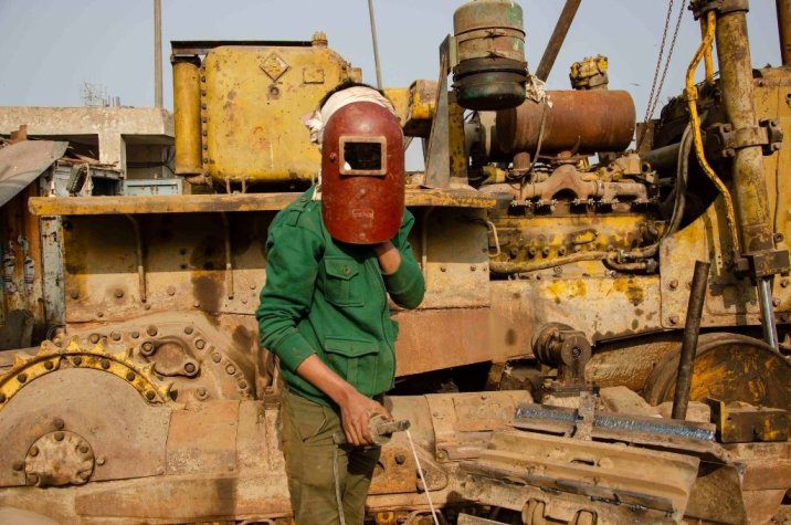 A mechanic wearing a welding mask
in front of a machine at the Ghazipur landfill near New Delhi-waste management