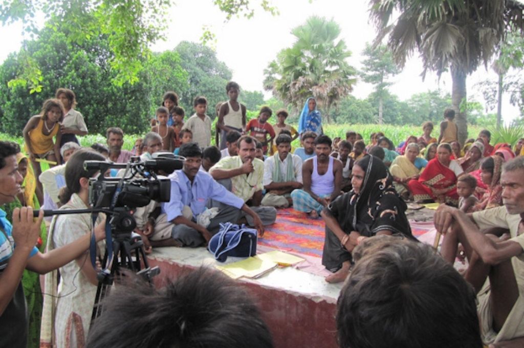 Reporters interviewing people who have gathered around, with a mic and a video camera-media