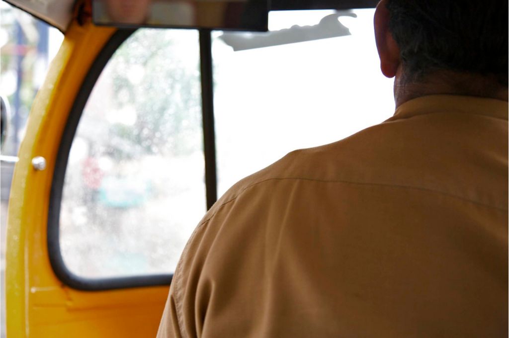 back profile of an auto driver sitting in his autorickshaw - labour welfare