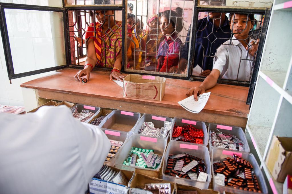 People wait at the window to get medicines at a community health centre_public healthcare system