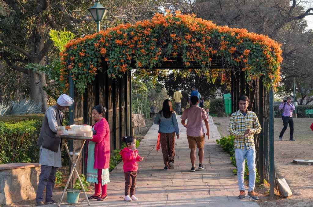 People outside a park entrance made of flower arch_cities