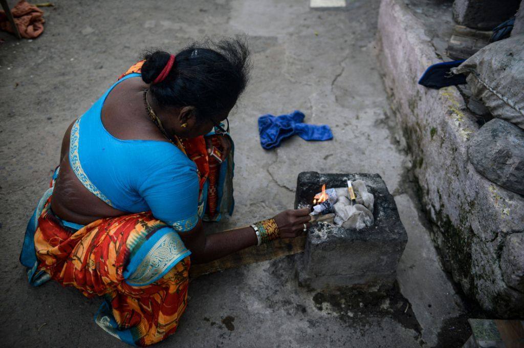 A woman putting firewood into a chulha_air pollution