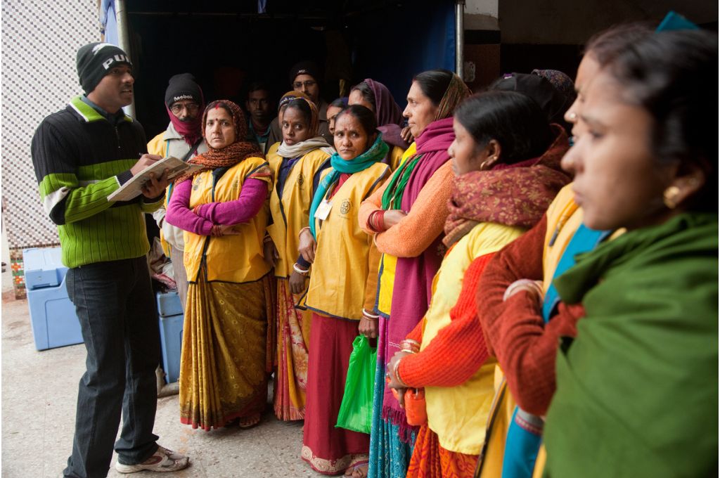 Women assembled together in uniforms as a man talks to them with a clipboard in hand-behavioral science