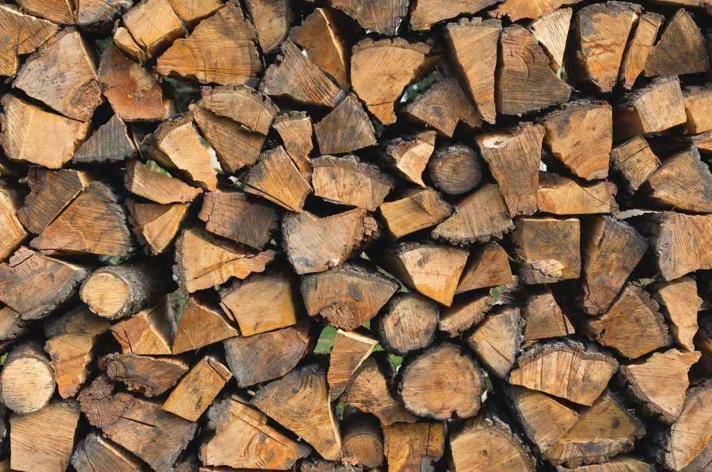 The image is a close-up of rows of chopped firewood stacked on top of each other._Burning firewood